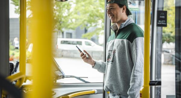 Foto av person som med mobiltelefon i handa som går om bord i bussen